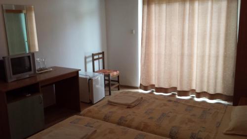 a bedroom with a bed and a tv and a window at Hotel Diva in Ravda