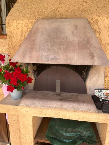 un four à pizza en pierre avec des fleurs rouges sur une table dans l'établissement Tlb, à Saint-Cyr-sur-Mer
