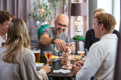 a group of people sitting around a table playing chess at Home Hotel Uppsala in Uppsala