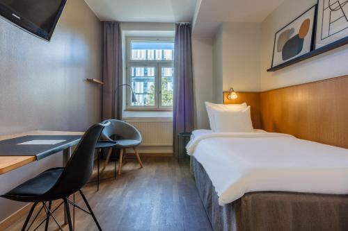 a hotel room with a bed and a desk at Home Hotel Uppsala in Uppsala