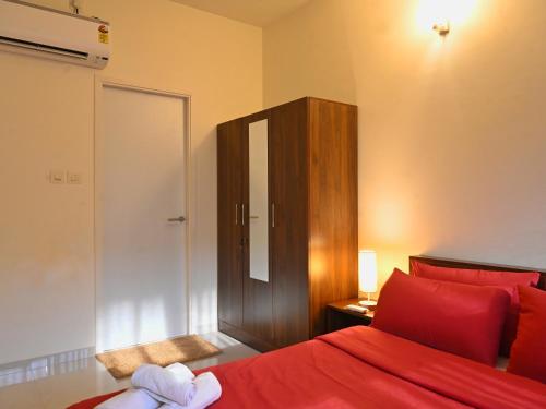 a bedroom with a red bed and a wooden cabinet at No Fixed Address in Marmagao