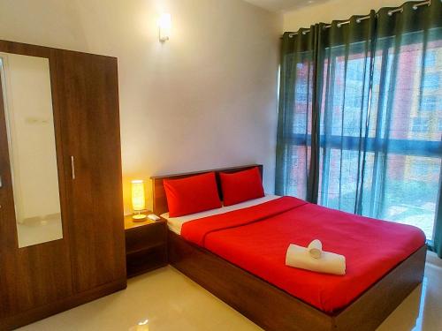 a bedroom with a bed with red sheets and red pillows at No Fixed Address in Marmagao
