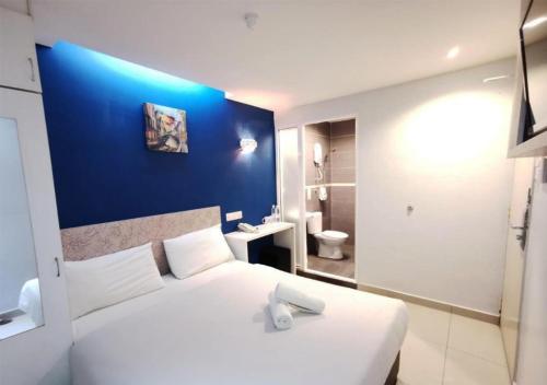 a bedroom with a white bed and a blue wall at Mozu Hotel Sri Hartamas in Kuala Lumpur