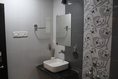 W białej łazience znajduje się umywalka i lustro. w obiekcie Hotel Skylark w mieście Vapi