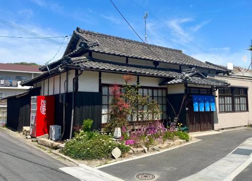 a small house with flowers on the side of the street at Hoshikuzu in Naoshima