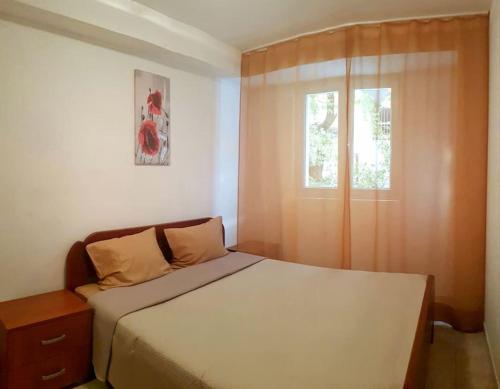 een kleine slaapkamer met een bed en een raam bij Apartment with a garden Petrovac in Petrovac na Moru