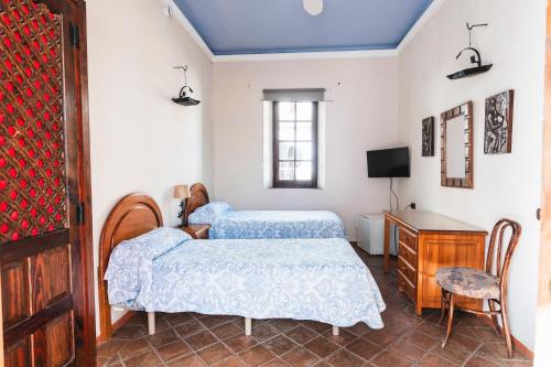 a bedroom with two beds and a desk and a tv at Hotel Balneario De Sierra Alhamilla in Pechina