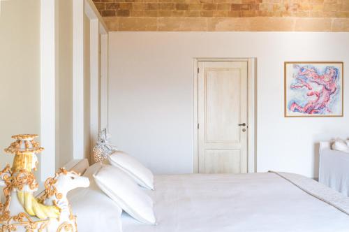 Dormitorio blanco con cama blanca y cabecero de caballo en Masseria Fontana di Vite, en Matera