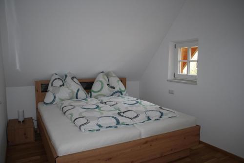 uma cama num quarto branco com uma janela em Ferienhaus Schirgi em Sankt Kathrein am Offenegg