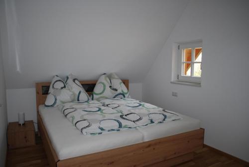 a bed in a white room with a window at Ferienhaus Schirgi in Sankt Kathrein am Offenegg