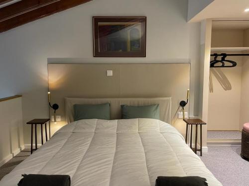 a bedroom with a large white bed with two tables at Calming Mountain View Apt with Balcony & Free Parking near Kakopetria in Nicosia