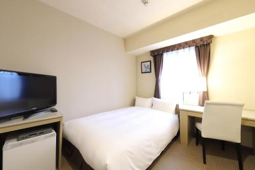 a hotel room with a bed and a desk and a television at Shin-Yokohama Kokusai Hotel in Yokohama