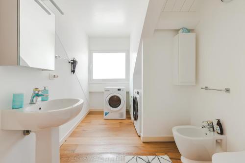 a white bathroom with a sink and a washing machine at Attico Riva Mare in Muggia
