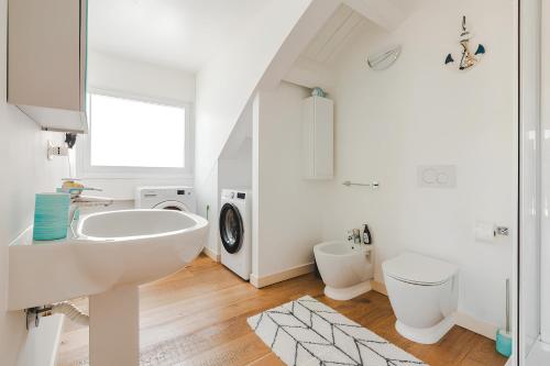 a white bathroom with a sink and a washing machine at Attico Riva Mare in Muggia
