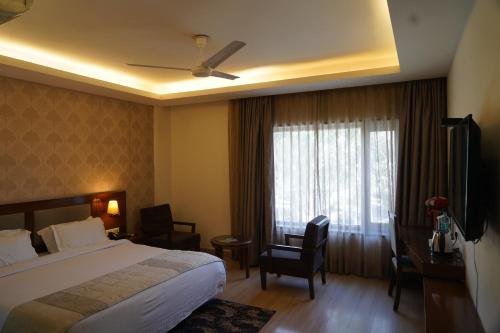 a hotel room with a bed and a desk and a window at Hotel Forest Avenue - Best Luxury Hotel in Dehradun in Dehradun