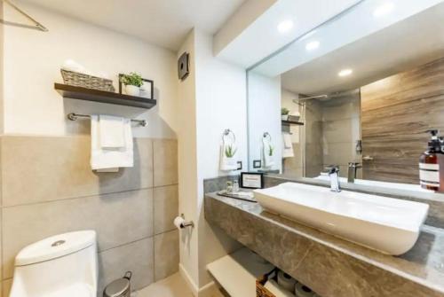 y baño con lavabo, aseo y espejo. en Central Park Jr. Suites en Quetzaltenango