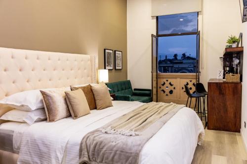 Un dormitorio con una cama grande y una ventana en Central Park Jr. Suites, en Quetzaltenango
