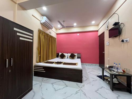 a bedroom with a bed and a pink wall at Hotel Saan Berhampore in Baharampur