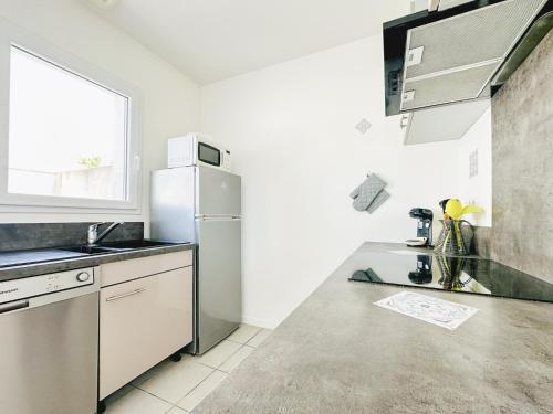 une cuisine avec un évier et un réfrigérateur dans l'établissement Maison de vacances rénovée calme et lumineuse - 4 pers, à Les Sables-dʼOlonne