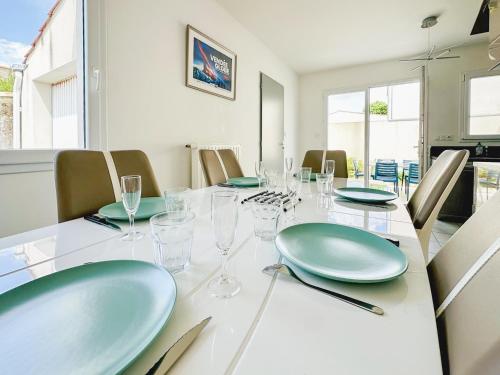 une salle à manger avec une table et des verres verts dans l'établissement Maison de vacances rénovée calme et lumineuse - 4 pers, à Les Sables-dʼOlonne