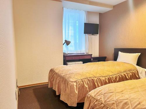 a hotel room with two beds and a window at Hotel Sho Sapporo in Sapporo