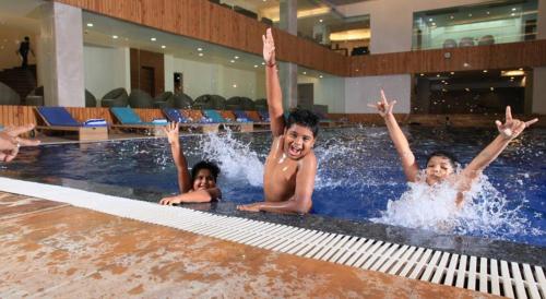 een groep kinderen die zwemmen in een zwembad bij Hotel Grand Canyon in Raipur