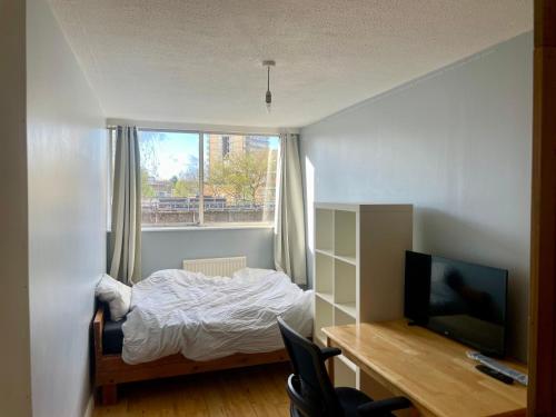 a bedroom with a bed and a desk and a television at Heart of West London in London