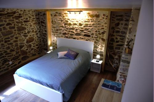 1 dormitorio con cama y pared de piedra en Maisonnette et gîte proches de la mer, en Plouha