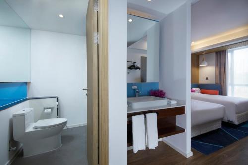 a bathroom with a toilet and a sink and a bed at Holiday Inn Express Zhangjiagang East, an IHG Hotel in Zhangjiagang