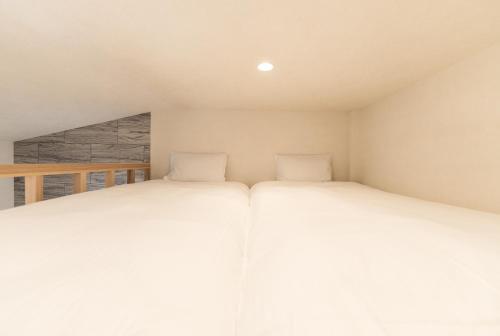 two beds in a small room with white walls at Flower Base Lily House in Fukuoka
