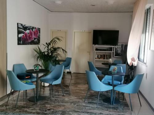een eetkamer met blauwe stoelen en tafels en een tv bij Hotel Silvana in Bellaria-Igea Marina
