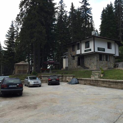 a house with cars parked in a parking lot at Семеен хотел Гингеръ in Pamporovo