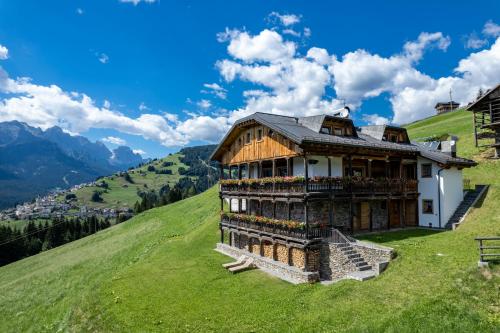 a building on top of a hill with mountains at Agriturismo Botondoro in San Nicol&ograve; di Comelico