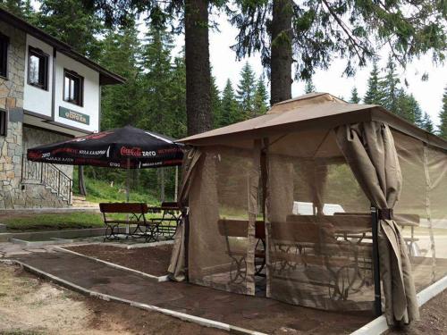 a tent with a table and an umbrella at Семеен хотел Гингеръ in Pamporovo