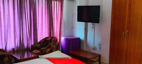 Habitación con cama, TV y silla. en HOTEL MANHATTAN en Chennai