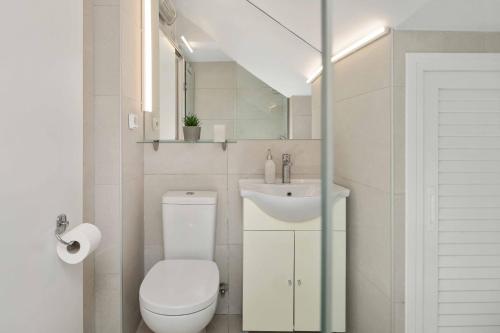 Un baño blanco con inodoro y lavabo. en Yard Studio by CorfuEscapes, en Corfú