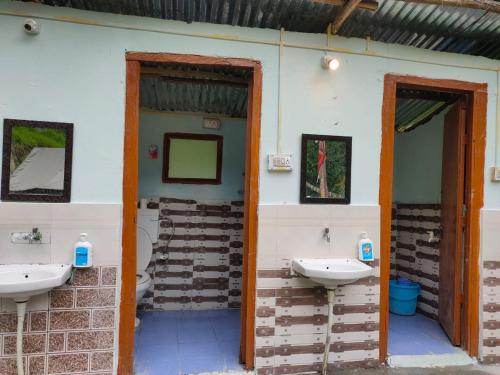 uma casa de banho com dois lavatórios na parede em Himtrek Camps Jibhi em Jibhi