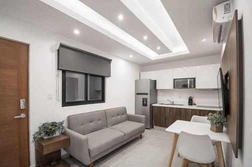 a living room with a couch and a kitchen at Joya de la Zazil 20 Av ROOFTOP POOL Walk to Playa Mamitas Coco Beach & 5 in Playa del Carmen