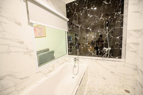 a white bathroom with a tub and a window at Marble Arch De Loei Hotel in Loei