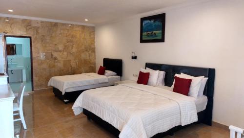 Grand Melka Hotel في لوفينا: غرفة فندقية بسريرين وجدار حجري