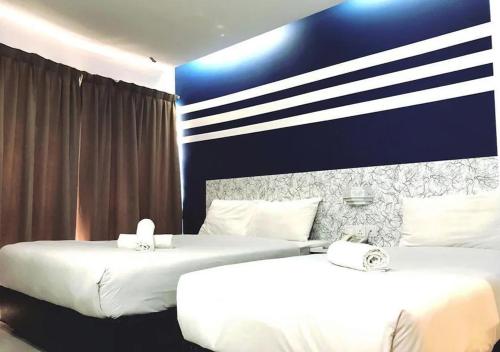 two beds in a hotel room with white sheets at Mozu Hotel Sri Hartamas in Kuala Lumpur
