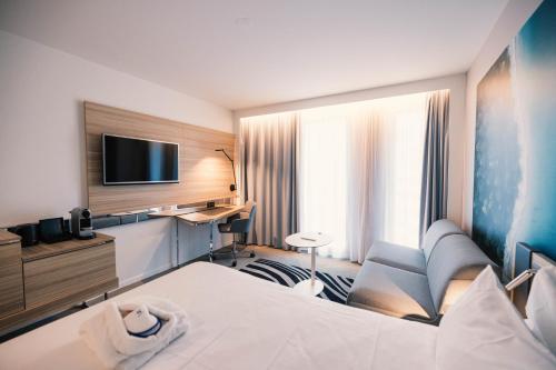 a hotel room with a bed and a flat screen tv at Novotel Le Havre Centre Gare in Le Havre