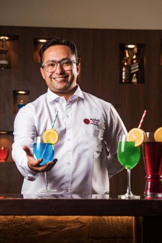 a man standing in a bar holding two cocktails at Manas Lifestyle Resort, Igatpuri in Igatpuri