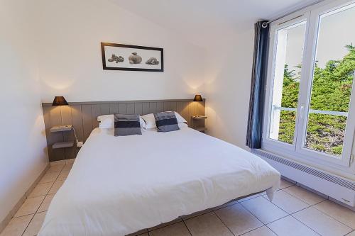 une chambre avec un grand lit blanc et une fenêtre dans l'établissement Le Moulin des Sables, à La Flotte