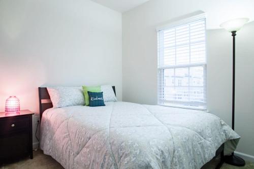 Habitación blanca con cama y ventana en Large MD Townhome mins to UMD & DC Parking, en Greenbelt