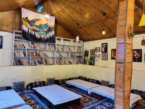 una habitación con mesas y estanterías de libros en Himtrek Camps Jibhi en Jibhi