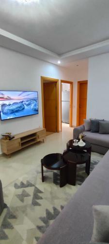 ein Wohnzimmer mit einem Sofa und einem TV an der Wand in der Unterkunft Appartement de Luxe sur Témara in Temara