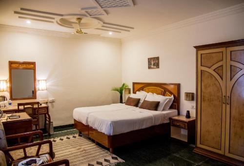 a bedroom with a bed and a desk and a mirror at Hotel Ranthambore Regency in Sawāi Mādhopur