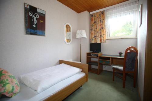 a bedroom with a bed and a desk with a computer at Pension Weinberg mit Landhaus Nizza in Gleisweiler