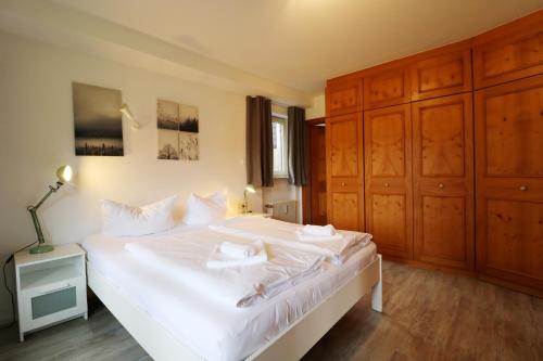 una camera da letto con un grande letto bianco e armadi in legno di Hus im Schwefelmättle, Hinterzarten a Hinterzarten